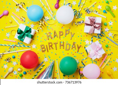 Happy birthday background or greeting flyer. Colorful holiday supplies on yellow table top view. Flat lay style.