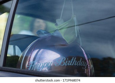 Happy Birthday Baloon In The Back Seat Of A Car With A Surgical Mask Hanging Overhead