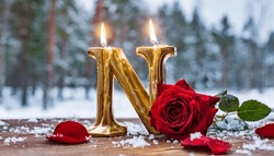 Happy Birthday Candle In The Shape Of The Alphabet Letters On A Table. Red Rose, Rose Leaves Scattered On The Table With Snow, In Winter.