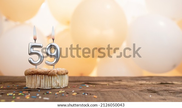 Happy birthday card with candle number 59 in a\
cupcake against the background of balloons. Copy space happy\
birthday for fifty nine years\
old