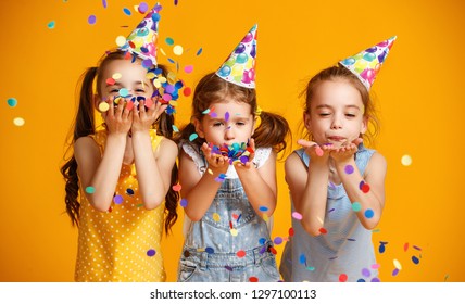 happy birthday children girls with confetti on  colored yellow background
