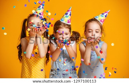 happy birthday children girls with confetti on  colored yellow background