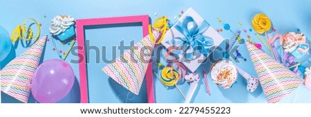 Happy birthday greeting card background. Flatlay with colorful holiday tools - birthday party caps, blowers, gift boxes , balloons, steamers, candles, on blue background copy space