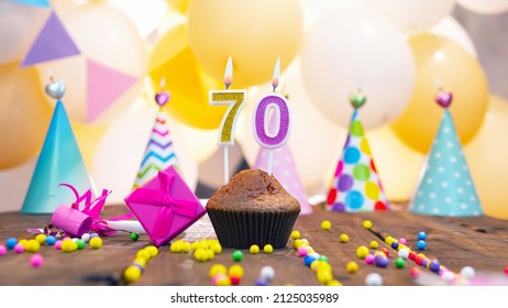 Happy birthday with a number of candles for seventy years on the background of balloons. A festive muffin with burning candles and a pink gift box for a woman. Happy birthday for 70 years - Shutterstock ID 2125035989