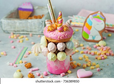 Happy Birthday party background: Freak shake topping with donut decorated as unicorn on the grey background; selective focus. 