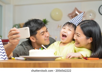 Happy Birthday Party In Family, Asian Young Parent Father, Mother And Little Cute Boy Or Child Celebrating, Using Smart Phone Selfie, Take Photo And Video Call During Celebration  Together At Home.