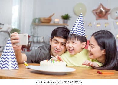 Happy Birthday Party In Family, Asian Young Parent Father, Mother And Little Cute Boy Or Child Celebrating, Using Smart Phone Selfie, Take Photo And Video Call During Celebration  Together At Home.