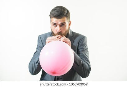 Happy birthday, preparation to party, celebration - attractive businessman with beard and mustache is blowing pink balloon. Stylish man in suit inflating balloon. Handsome bearded man hold air balloon