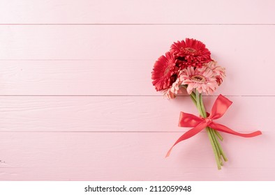 Happy birthday. Red gerbera daisy flowers and blank craft label tag on pink wooden table, flat lay - Powered by Shutterstock