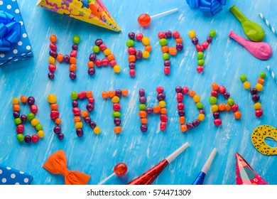 Happy Birthday sign of small jelly beans on a blue background. Red, yellow, orange and green items for a party, noisemakers, lollipops. Especially for your loved one. - Powered by Shutterstock