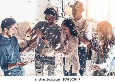 Happy birthday! Top view of happy young man celebrating birthday among friends while standing in room with confetti flying around - Shutterstock ID 1099303949