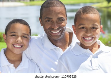 A Happy Black African American Family Of Father Parent And Two Children, Two Boy Sons, Sitting Together Outside.