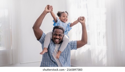Happy black African American father daughter playing at home living room. Afro man carry piggyback little toddler girl. Cheerful family bonding together father’s day concept banner with copy space - Shutterstock ID 2165897383