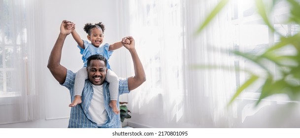 Happy black African American father daughter playing at home living room. Afro man carry piggyback little toddler girl. Cheerful family bonding together father’s day concept banner with copy space - Powered by Shutterstock