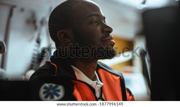 Happy Black African\
American Paramedic Tries to Rest in an Ambulance Vehicle Going for\
Emergency. Emergency Medical Technicians are on Their Way to a\
Call. Close-up Shot.