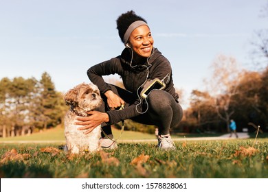 Happy Black Athletic Woman And Her Dog Enjoying In A Day In Nature. 