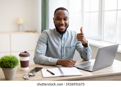 Happy Black Businessman At Laptop Gesturing Thumbs-Up Posing Smiling To Camera Sitting In Modern Office. I Like My Business And Entrepreneurship Career Concept.