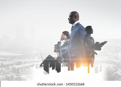 Fröhlicher schwarzer Geschäftsmann mit anderen Leuten, die im Büro auf städtischem Hintergrund arbeiten