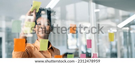 Happy black businesswoman planning new porject with sticky note in a creative office