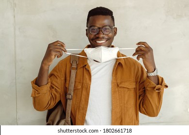 Happy Black College Student Holding His Protective Face Mask And Looking At Camera. 