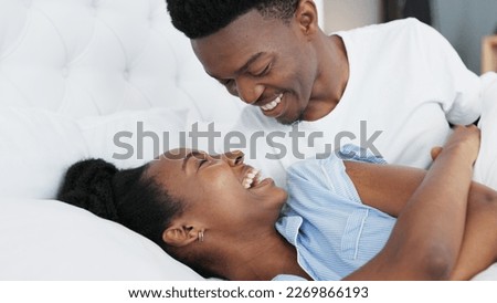 Happy black couple in bedroom kiss and smile for love, romance and intimacy at house or home in morning. Young, happiness and kissing black woman and man or romantic black people dating bond together