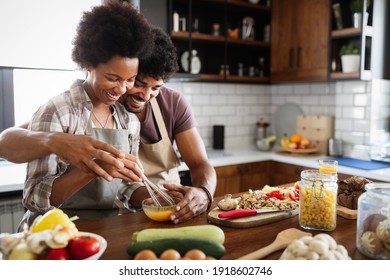 Happy black couple cooking and tasting healthy food in kitchen