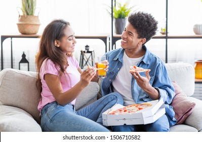 Happy Black Couple Eating Pizza And Having Drinks On A Date At Home