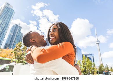 Happy black couple having fun in Toronto - Man and woman embracing and laughing in the city during the day - Lifestyle and friendship or love concepts - Powered by Shutterstock
