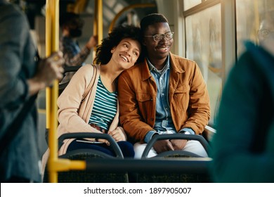 Happy black couple looking through the window while commuting by public transport.