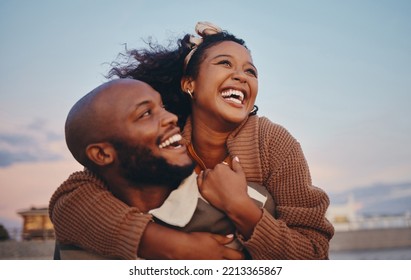 Happy black couple, love and hug laughing in joyful happiness for bonding time together in the outdoors. African American man and woman enjoying playful fun piggyback with smile for holiday in nature - Shutterstock ID 2213365867