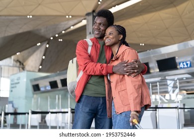 Happy Black Couple In Love Wait For Flight In Airport. Young Romantic African Man And Woman Before Departure For Vacation Or Honeymoon Trip Hug And Smile. Casual Afro Guy And Girl Travel By Plane