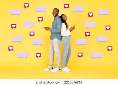 Happy Black Couple Texting On Phones Posing Standing Back To Back On Yellow Background With Hearts And Message Icons. Dating Application And Mobile Communication. Collage, Full Length