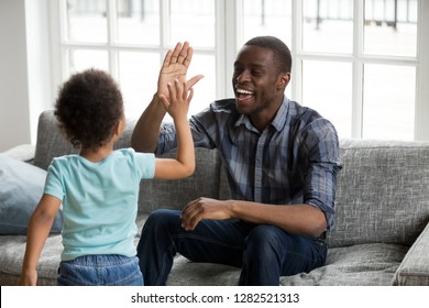 Happy Black Dad And Little Son Giving High Five Playing At Home, Excited African Single Father And Toddler Cute Kid Boy Laughing Enjoying Clapping Hands Having Fun Together, Daddy Child Friendship