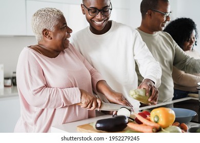 Happy black family cooking inside kitchen at home - Main focus on mom face