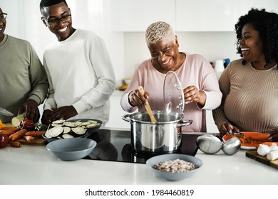 Happy black family cooking vegan food inside kitchen at home - Focus on mother face - Powered by Shutterstock