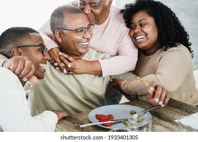 Happy Black Family Eating Lunch At Home - Father, Daughter, Son And Mother Having Fun Together Sitting At Dinner Table - Main Focus On Man Face