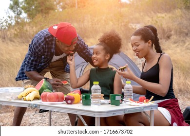 Happy black family with girl in forest. African american family  eating food during picnic.