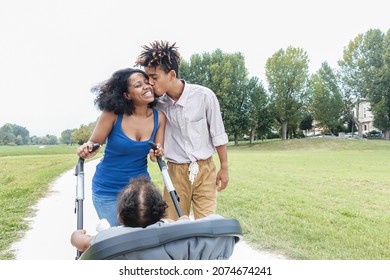 Happy Black Family Having Fun Walking With Stroller Outdoor At City Park - Soft Focus On Woman Face