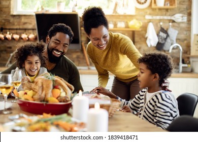 Happy Black Family Having Roast Turkey For Lunch While Celebrating Thanksgiving At Home. 