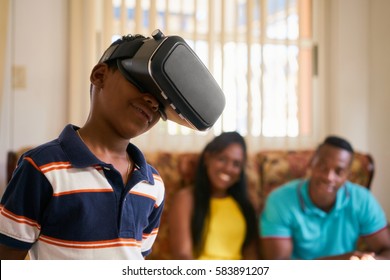 Happy black family at home. African american father, mother and child. Man, woman and boy playing with virtual reality goggles, VR headset, modern technology glasses - Powered by Shutterstock