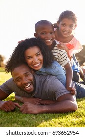 Happy Black Family Lying In A Pile On Grass Outdoors