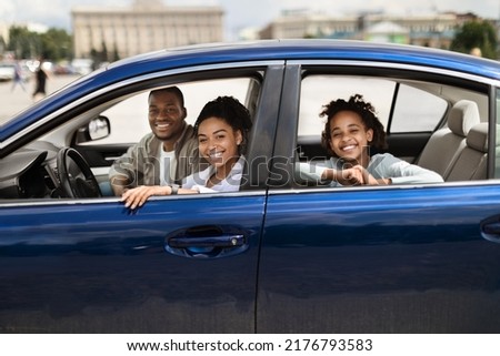Happy Black Family In New Blue Car Posing Smiling To Camera Having Ride In City. Parents And Preteen Daughter Sitting In Luxury Auto. Automobile Ownership And Purchase Concept. Selective Focus