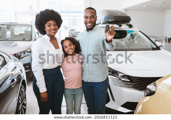 Happy\
black family posing with new car key, buying or renting automobile\
at auto dealership. Cheerful African American parents and kid\
purchasing vehicle together at automotive\
showroom