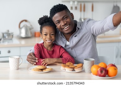 Happy Black Family Single Father And Little Daughter Taking Selfie While Having Breakfast Together At Home, Sitting At Kitchen Table, Embracing And Smiling At Camera, Copy Space