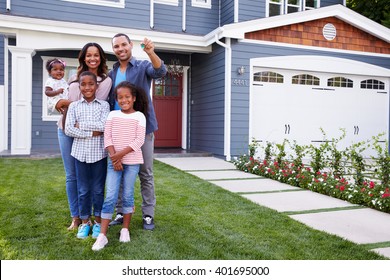 Happy black family standing outside their house, dad holding the key