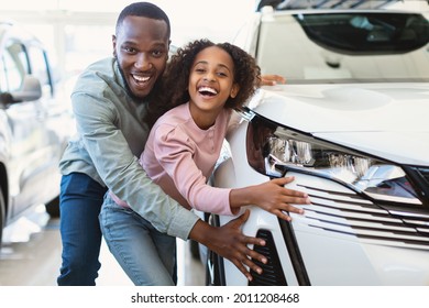 Happy Black Father And His Cute Daughter Selecting New Car, Buying Or Renting Automobile At Auto Dealership. Cheerful Afro Family Choosing Vehicle Together At Automotive Showroom