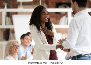 Happy black female employee get rewarded for professional achievement handshake boss, tolerant male manager shake hand of proud african business woman promote express recognition at work concept