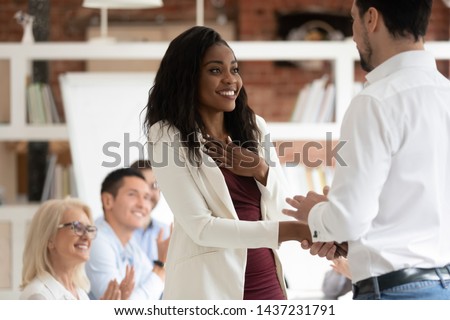Happy black female employee get rewarded for professional achievement handshake boss, tolerant male manager shake hand of proud african business woman promote express recognition at work concept
