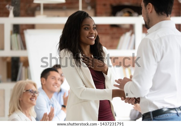 Happy black female employee get rewarded for\
professional achievement handshake boss, tolerant male manager\
shake hand of proud african business woman promote express\
recognition at work\
concept