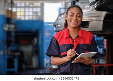 Happy Black female supervisor mechanic, cheerful smile, inspects repair work checklists with tablet at garage, service car maintenance, and fixing specialist occupations in auto transport industry. - Powered by Shutterstock